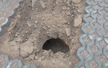 Głębokie zapadlisko z luźną ziemią i kamieniami widoczne w nawierzchni z kostki brukowej to wynik awarii wodociągu.